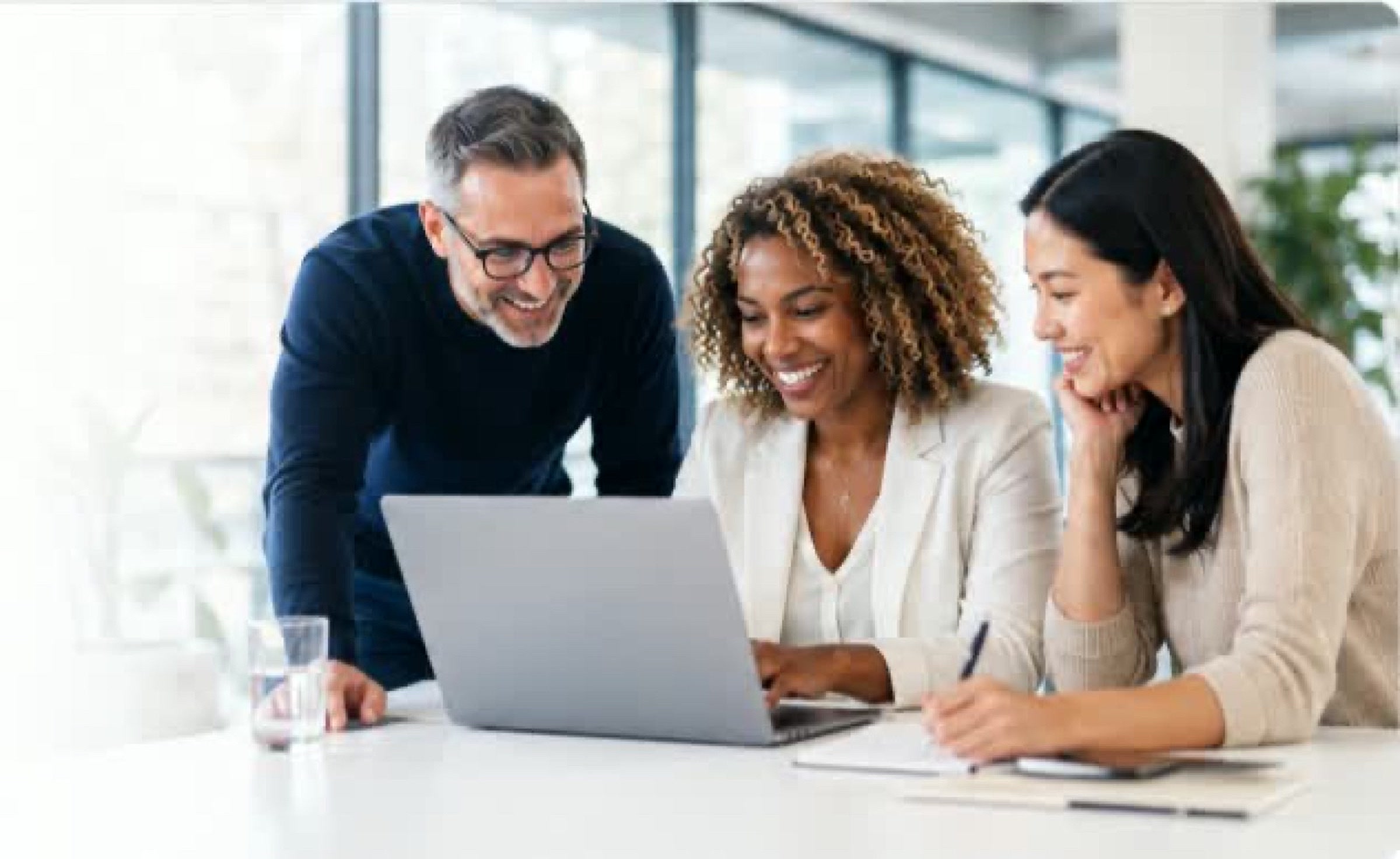 A professional team reviewing content on a laptop in a bright office.